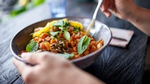 Hand holding a bowl of chickpeas and vegetables with mint